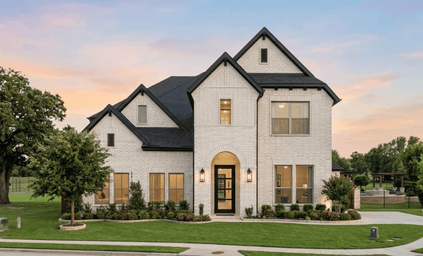 A well-lit two-story home at dusk with warm interior lights
